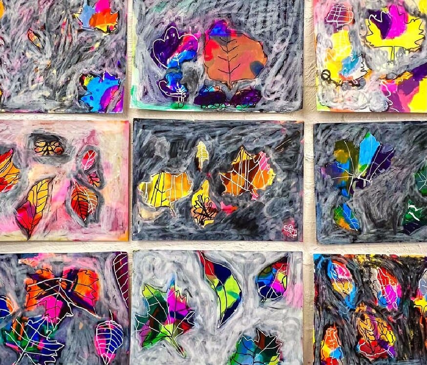 A wall of children's leaf paintings in bright pink, yellow and blue